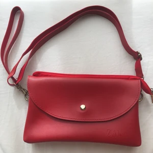 röd handväska från zara - Röd handväska från zara i fake läder, två ytterfack och ett fack i mitten. Ca 22x13 cm! Möts i slussen eller postar!