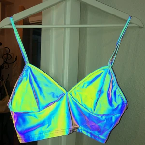 Unik partytopp som reflekterar  - Säljer min unika partytopp som reflekterar i nattklubsljus, perfekt för fest eller rave!! Är inköpt på en vintage butik i Köpenhamn 💛 Första bilden är tagen med blixt för att visa hur de reflekterar mot ljus⚡️ Utan blixt/nattklubbsljus är den i färgerna mörk grön/lila