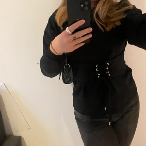 Svart sweatshirt med korsett - Svart lång sweatshirt med korettdetalj i midjan. Köpt på na-kd i strl S. Är i bra skick. Priset kan diskuteras! Hör gärna av dig om du har frågor!💕
