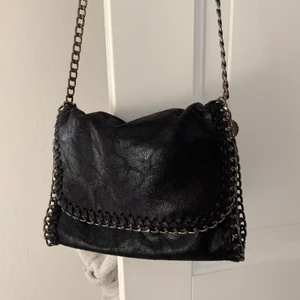 Axelremsväska - En liten svart skimrig Stella Mccartney inspirerad väska med kedjor i lite mörkare rostig metall! Använd en del men i fint skick o kommer inte till användning längre 🖤