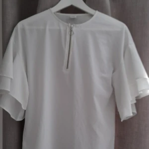 Vit blus - Jag säljer denna helt oanvönda blusen för att ja köpt den i fel storlek. Den är köpt på lindex. Det är en silvrig dragkedja fram som design