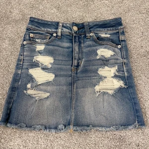 Jeanskjol med slitningar - Jag säljer en jeanskjol med slitningar från American Eagle Outfiters! Supersnygg men har tyvärr blivit för liten. (Köparen betalar frakten)💗💓💞💕
