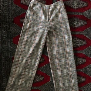 Vida rutiga kostymbyxor - Ett par rutiga byxor med vida ben och högmidjade! Dragkedja och knapp. Använda 1 gång. Storlek 36! Skriv för fler bilder/mått! Allt så bort på min sida pga flytt! Priser går att diskutera! :) 