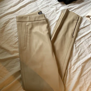 Byxor  - Byxor från zara i läderimitation. Beiga och bra skick. Dragkedjor längst ned. Sitter som xs 