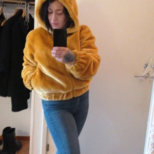 STAY J NAOMI Höst/vinterjacka strl M - Senapsgul fauxfur med stor luva. Slutar lite nedanför midjan, alltså trendigt kort. Dragkedja, fickor, rymlig men med riktigt snygg passform. Har även en i mörkblått. Oanvänd pga dubbelköp. Inköpt för 600 kr. 