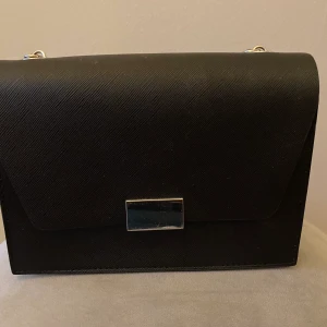Svart handväska  - Säljer väskan eftersom den inte kommer till användning. Den är i nyskick. Nypris: 169kr.