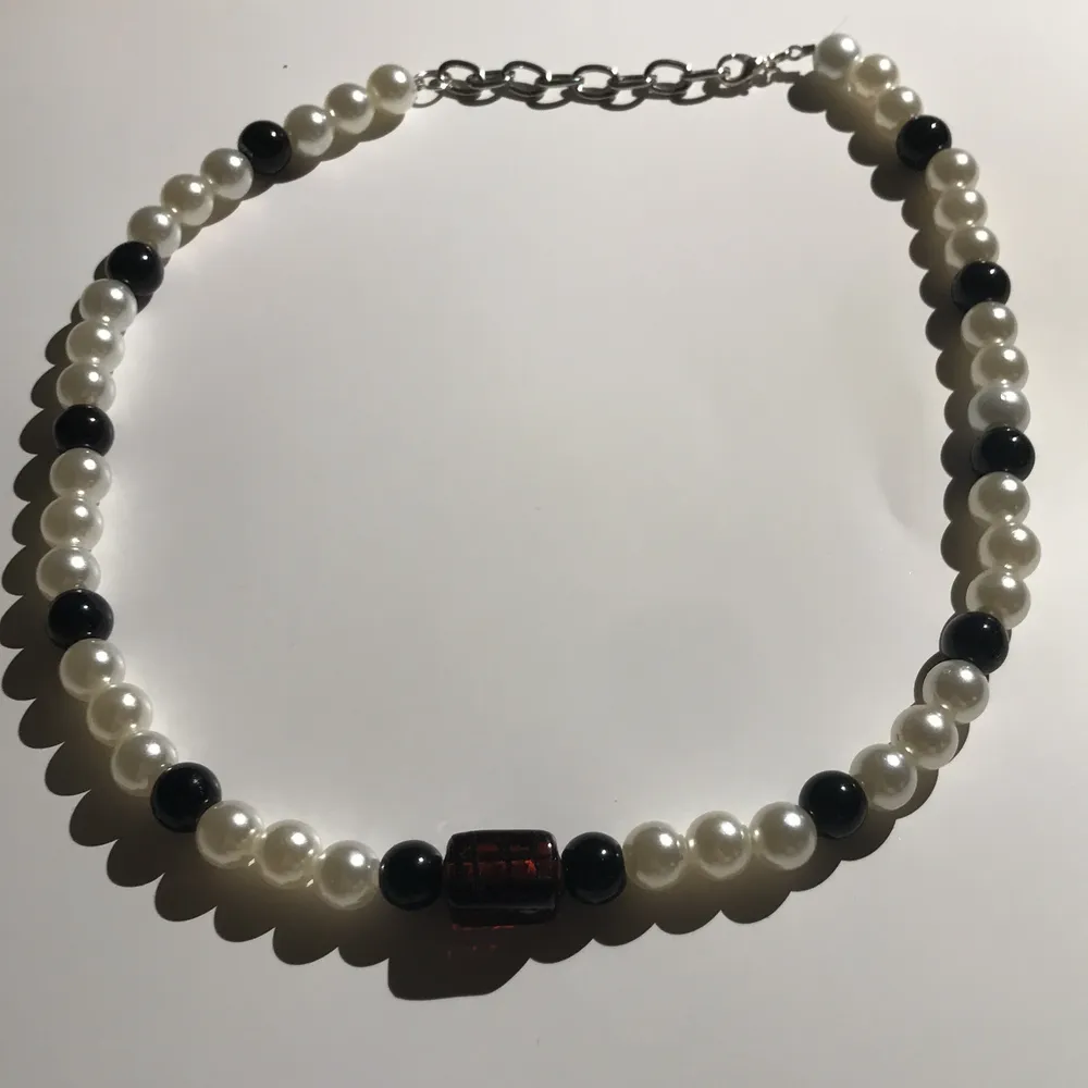 Pärlhalsband svarta & vita pärlor med en svart & brun pärla i mitten, går att gör längre och kortare . Accessoarer.