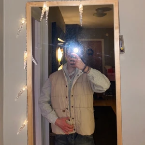 vändbar väst. vit & beige - vändbar. en beige väst och en vit beige i samma. med två stora fickor på magen.