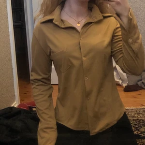 Beig skjorta  - En superfin och skön skjorta i beiga/brun. Skjortmodell men materialet är tjockare och mjukare. En ficka på vänster sida och den är lite figursydd.