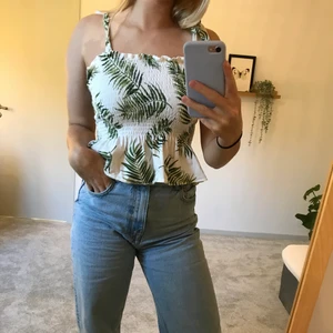 Mönstrad Tröja från H&M med palmer på - En jätte söt och fin ribbad tröja från hm med små palmblad på och knyten på axelbanden som är reglerbara samt lite volang längst ner vid tröjan. Tröjan hann aldrig komma till användning men är jätte fin och i toppenskick, köparen står för frakten💞