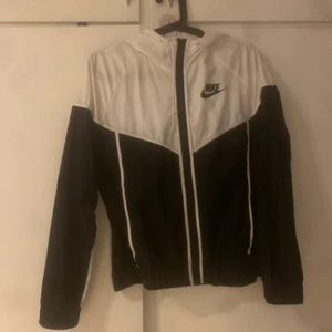 Nike vindjacka. - Stl S. Knappt använd liten reva i tyget, se bilden. Finns i Västerås. Köparen står för eventuell frakt.