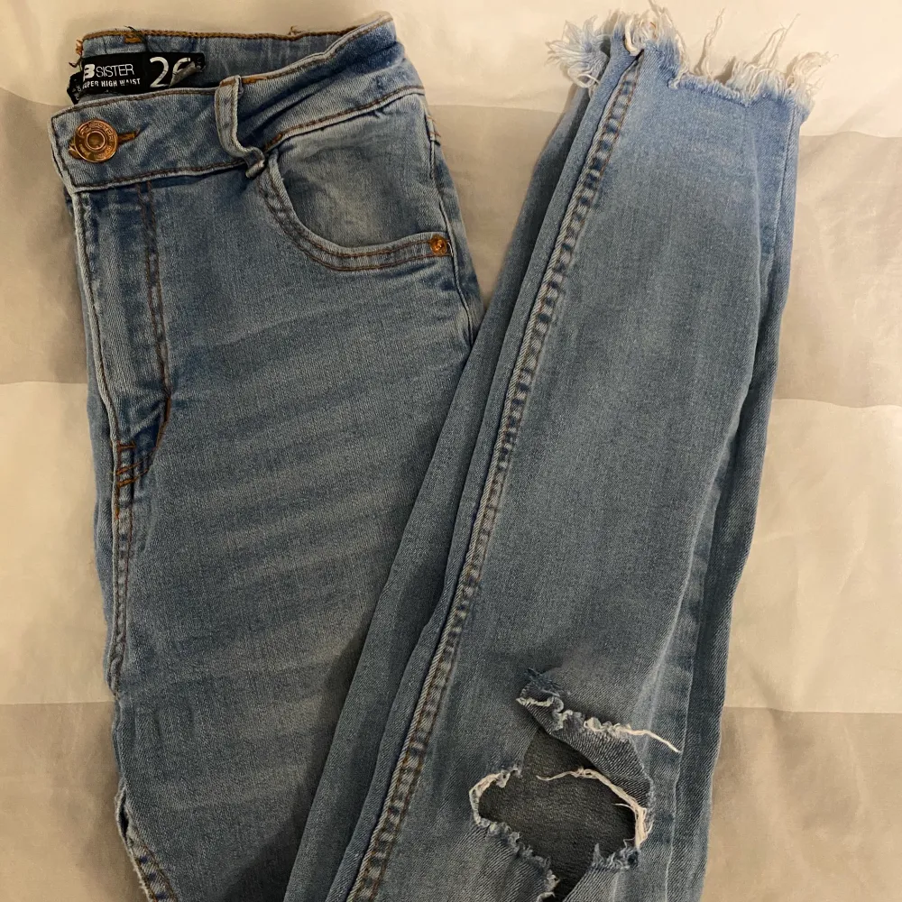 ljusblåa skinnyjeans med hål i knäna och slitningar längst ner. Jeans & Byxor.