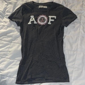 Abercrombie & Fitch T-Shirt  - Grå/mörkgrå med vitt och rosa tryck. Riktigt bra skick och skönt material ✨