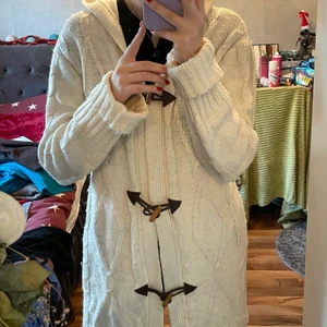 Lång vitt stickad kofta - Säljer denna super mysiga kofta i en benvit färg. Ärvde den från mamma, men den kom inte riktigt till användning. Den är lite längre och har även en luva🥰