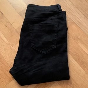 Svarta jeans med hål - Svarta stretchjeans från ASOS med konstgjorda hål i knäna. Storleken 30x30. Knappt använda.