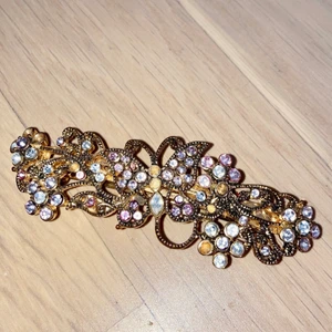 Brosch - Guldfärgad brosch med färgglada ”diamanter”. Några saknas men det syns inte. Cirka 9 cm lång. För mer information eller frågor, kontakta mig. Köparen står för frakten 💛