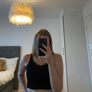 Svart topp med detaljer - Svart stickad topp med silvriga detaljer i fram. Använd ett fåtal gånger. Storleken är S, men kan töjas ut medan den är blöt! 