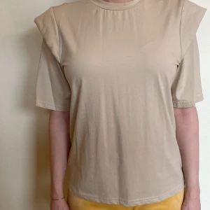 Beige cotton T-shirt with padded shoulde - This is a very comfortable and soft material, the color matches everything. It is in very good condition