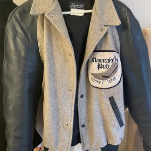 Varsity jacket - Grå Varsity jacka med mörkblå äkta läder ärmar, strl 44. Inköpt för ca 2 år sen på beyond retro för 899kr. Säljes då den inte kommer till användning. Plagget är i toppskick för att vara second hand och sitter oversize på mig som normalt bär strl S och är 155 cm lång. Passar S-XL beroende på önskad passform. Köparen står för frakten, alternativt kan jag mötas upp i Stockholm/ Sundbyberg. 