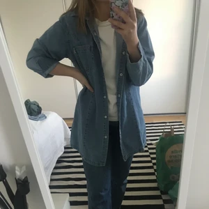 Jeansskjorta  - Lång jeansskjorta i jeansmaterial. Knappar fram och två fickor vid bröstet. Mycket bra skick. Oversize i modellen.