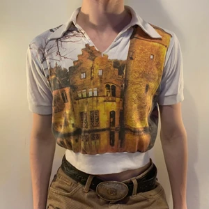 vintage vit all over print krage vit - Vit vintage croppad tröja med ett all over print av ett orange, gul och brunt slott på framsidan och med krage 🍂 Denna tröjan är helt perfekt för hösten både med motivet men också med färgerna! Så snygg till ett par manchesterbyxor, kängor och en stickad mössa för den riktiga höstliga viben! Den är också så bra att använda till layering då den har en spetsig! Eftersom den är kortärmad blir det heller inte lika tajt och obekvämt!