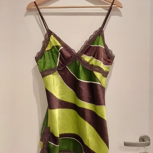 Brunt och grönt linne - Ett brunt/ grönt linne med spetsdetaljer. Trendiga färger och den där snygga spets criss-cross detaljen. Är längre i modellen med små spetsslitsar längst ner, men har stor potential som en crop top också;)