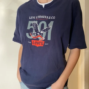  Vintage blå levis T-shirt med stort tryck på framsidan - Strl står inte på tröjan men den sitter som en s/m