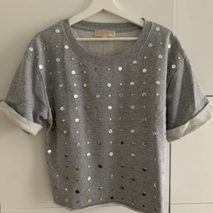 Michael Kors, topp (dam) - Grå topp/tshirt från MK i storlek M. Passar så snyggt på mig som vanligtvis har storlek S. Silvriga detaljer på framsidan och uppvika ärmar. Nypris ca 2000kr.                    Bjussar på frakten!
