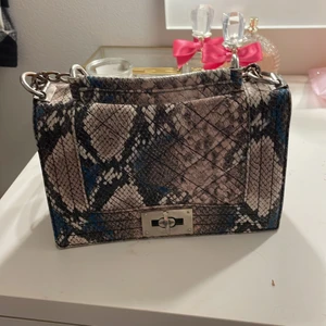 En Väska från ginatricot  - Det är en väska från ginatricot, hela väskan är i orm skin (de är inte äkta orm skin) den är i fint skick 