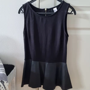 H&M topp med läder storlek 36 - Svart pepplum topp med fake läder nertill. Dragkedja i ryggen. Storlek 36 (small) från H&M. Använda med är i fint skick.