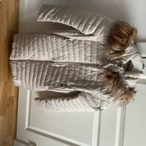 Odd Molly, vinterjacka - Knappt använd vinterjacka från Odd Molly. Färgen är lite gråbeige. Den är figursydd och går en bit nedanför rumpan. Varm och skön. Den är i strl 1 vilket är mellan S & M.