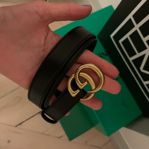 Gucci bälte  - Bälte i svart skinn och logga i guld från Gucci. Kartong och dustbag finns. 