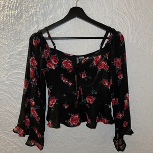 Oanvänd topp med blommor - Oanvänd topp från H&M i storlek 36/S. Rosett fram till brösten 