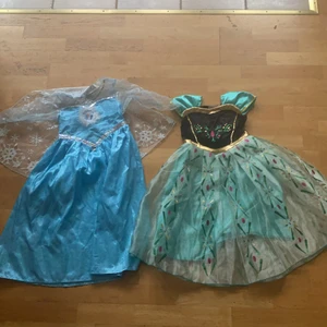 Frostkläklänningar,Frostleksaker - Anna och Elsa klänningar, Anna och Elsa tiaror, ett Frost pussel samt men Memory och en Frost högtalare.  Passar till flicka 4-6 år 