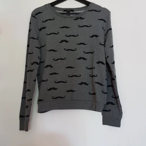 Forever 21 kofta - Forever 21 kofta med mustasch motiv. Aldrig använd. Storlek L. Liten i storleken.