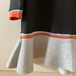 Supercool klänning  - Säljer denna superballa klänning. Bara använt en gång, så är basically ny. Funkar både att klä upp och ner. Klänningen har ett ganska stabilt tyg, vilket ger en lyxigare känsla. Volangen är grå och har detaljer i orange och även silvrigt/glitter. Ordinarie pris 499. Säljer för 250 exklusive frakt ✨🧡🖤