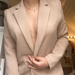 Skitsnygg beige kavaj - Knappt använd beige kanal i rak lång passform. Passar så fint till sommaren. Bältet till är borta men annars är den som ny! Fin färg och stilig passform.