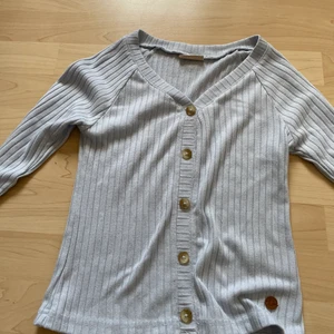 Kappahl blå tröja med knappar strl 146-152 - Säljer denna för att den är för liten. Bra skick! En blå långärmad ribbad tröja med knappar och v-ringning. Änvänd endast 10 gånger! !!köparen står för frakt!!