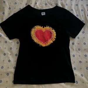 Y2k T-shirt  - En snygg tshirt från Urban outfitters som har en helt perfekt passform, både längd och storlek. Svart med coolt hjärta fram i rött och orange/gul. Behöver plats i garderoben därför säljs den😩 bara att skriva om man har frågor!!💕