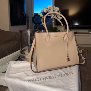 Michael kors väska - Säljer nu min super snygga Michael kors väska i beige med guld detaljer då den inte kommer till användning. Endast använd 2-3 gånger (nyskick). Materialet är läder och har måtten 32 x 24,5 x 14 cm. Väskan rymmer mycket men enkel att ta med sig. Det är en perfekt väska till både vardags och till de flesta tillfällen. Axelremsband och Michael kors påsen tillkommer såklart, även mindre fickor finns inuti väskan samt en större ficka (Skriv för mer bilder). 