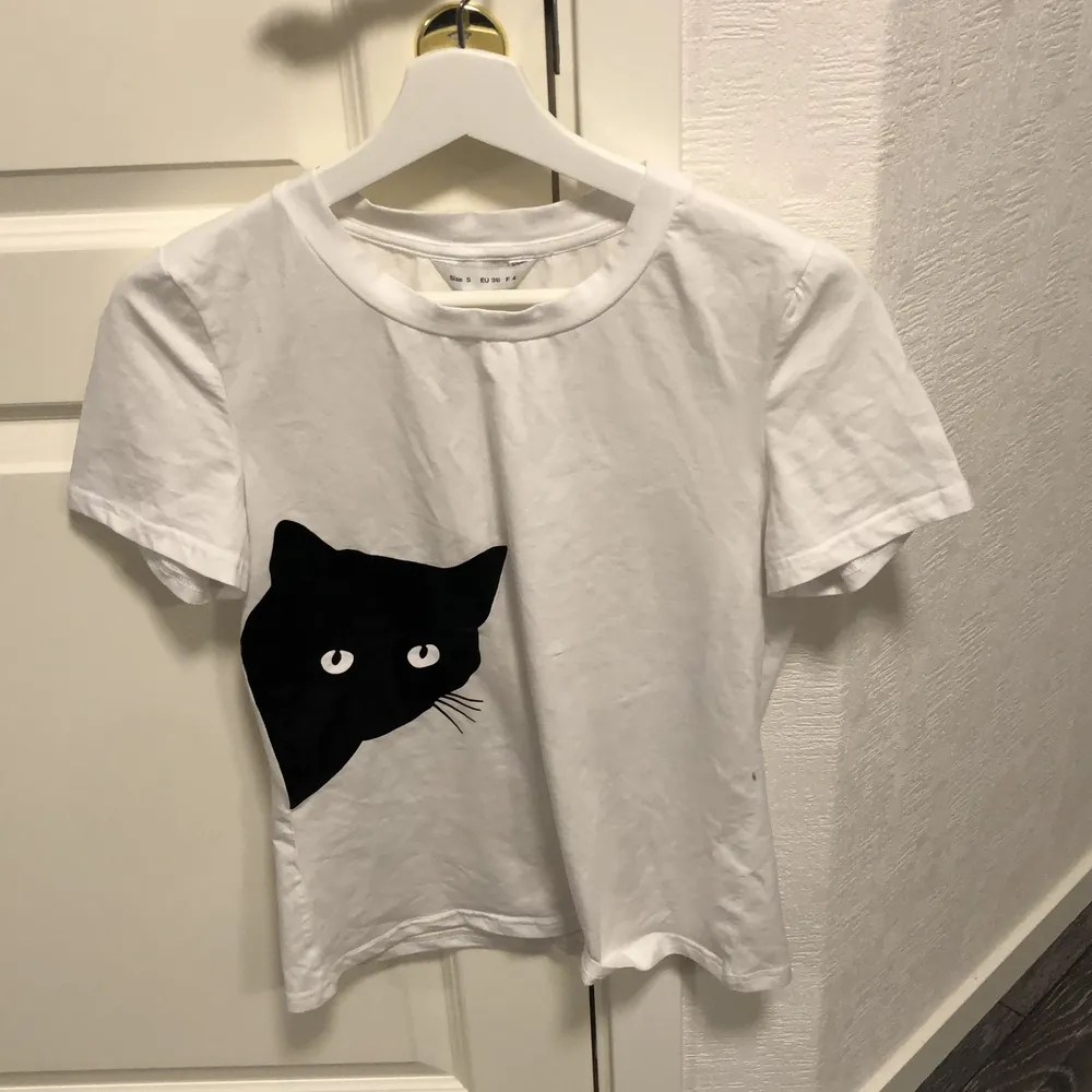 En vit t-shirt med en katt på framsidan. Aldrig använd. Frakt tillkommer . T-shirts.