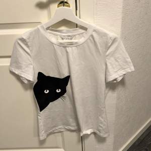 En vit t-shirt med en katt på framsidan. Aldrig använd. Frakt tillkommer 