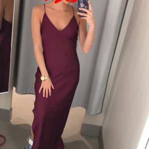 Mörklila långklänning  - Mörklila långklänning i storlek 34! Köpt från h&m för 499, finns ej kvar längre! Använd 1 gång på bal! Silkesliknande material med slits på ena sidan & djup rygg med korsade band! Består av en underklänning så att den ej är genomskinlig! Uppsydd så passar någon som är 160 (med klackar)! Frakt ingår i priset!