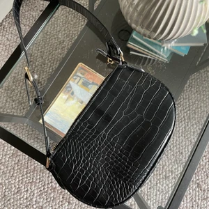 Svart Handväska - Svart handväska i ormskinnsimitation från Mango