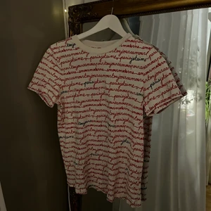 Vit t-shirt med röd och svart text - Vit t-shirt med röd och svart text.