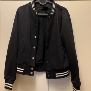 College Jacka från EMP - Svart college jacka med vita detaljer. Är köpt på EMP Shop för 549kr. Nästan aldrig använt den. Slutar vid höften, den är i S men känns mer som XS tycker jag. Vet inte hur mycket frakten blir. Skriv om du vill veta något mer☺️
