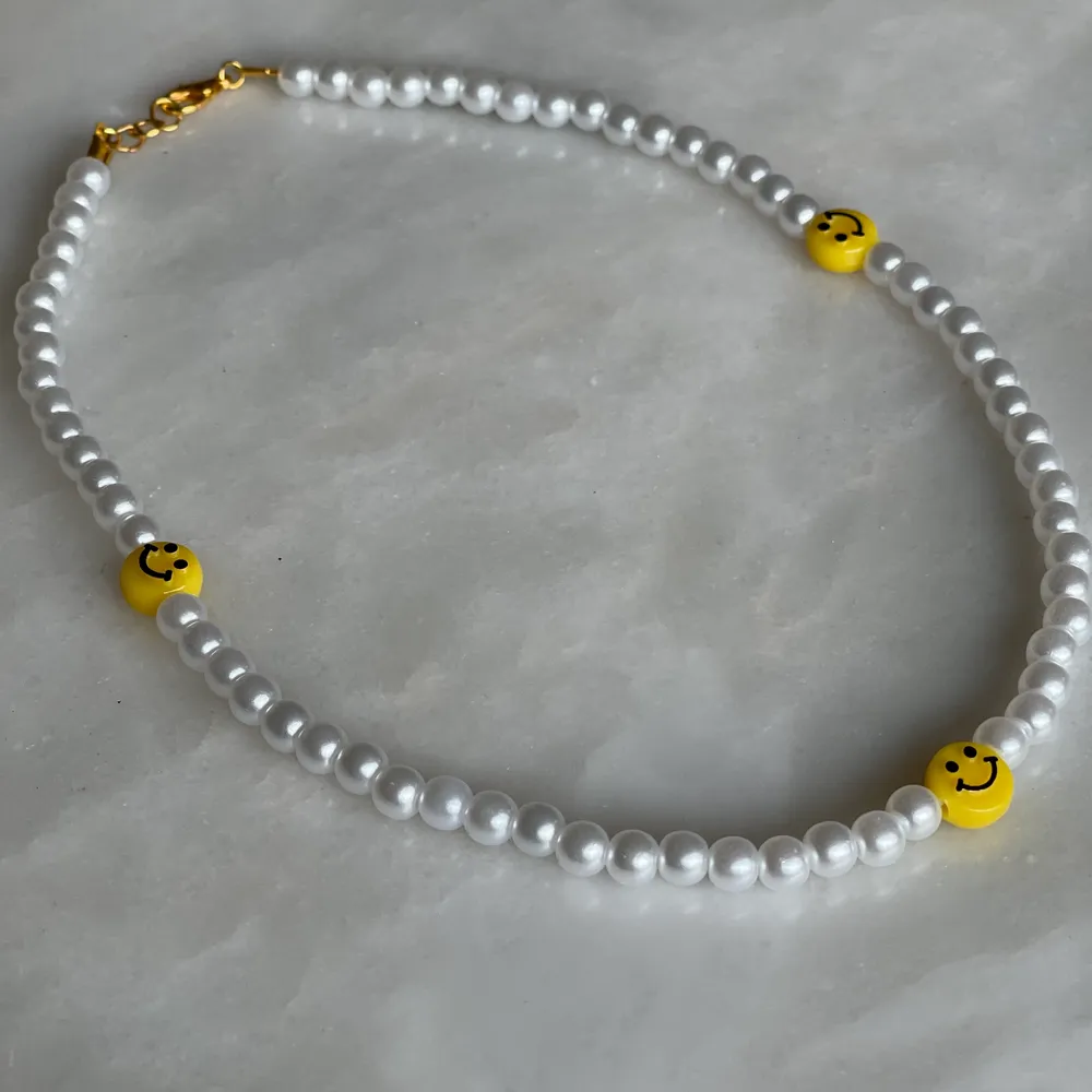 Ett super fint trendigt pärl halsband med tre smileys på.   Storlek 40cm, bandet är även elastiskt samt att det ingår spänne och ringödlor vilket gör att man kan justera halsbandet efter önskad storlek. . Accessoarer.