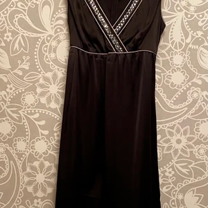 Partyklänning XS - Stilren klänning i glansigt material och glitter. Snörning i midjan med silvriga pärlor. 