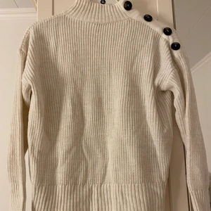 Stickad tröja - Vit stickad tröja. Är i bra skick. Har en fin passform. Är i storlek S. Har knappar på ena axeln.