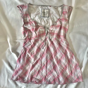 Rutig rosa topp - OM ANNONSEN FINNS KVAR FINNS PLAGGET KVAR! Söt rutig topp med gråa och rosa detaljer. Knyts med ett snöre ovanför brösten men även anpassbart under. Märkt storlek L men skulle säga att den även passar M beroende på önskad passform! Sitter även fint på mig som vanligtvis bär s. Gott second hand skick. Köpare står för 24kr frakt. 